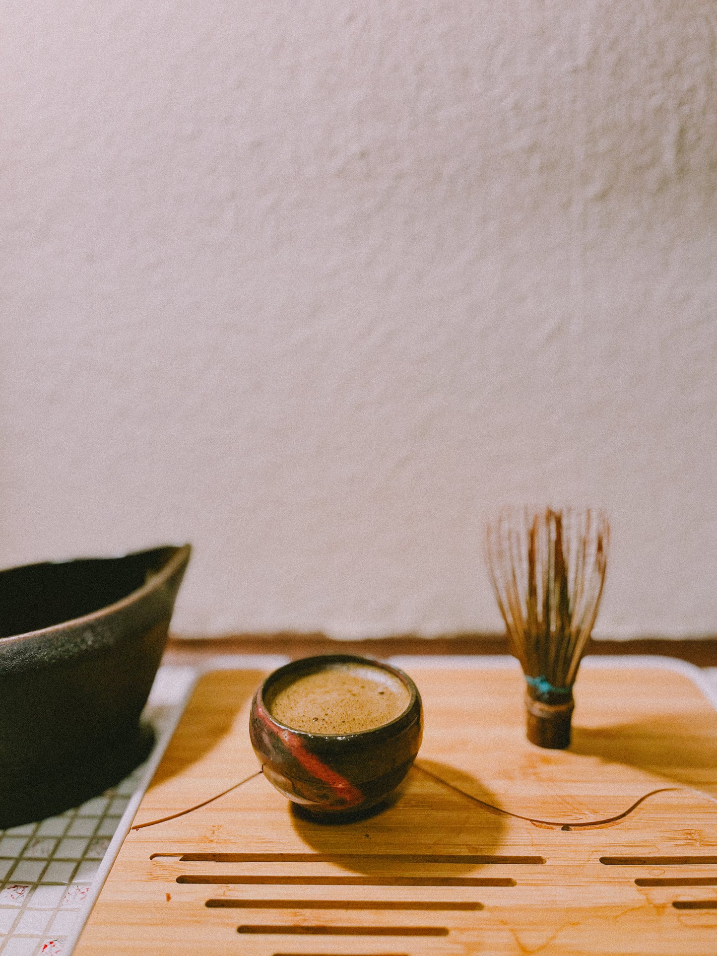 A small Chinese teacup holding a whisked shot of hojicha, roasted green tea. 